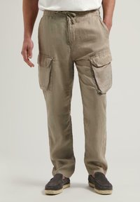Khaki plátenné cargo nohavice s elastickým pásom, šnúrkou a dvoma veľkými bočnými vreckami. Nosí sa s šedými espadrilkami.