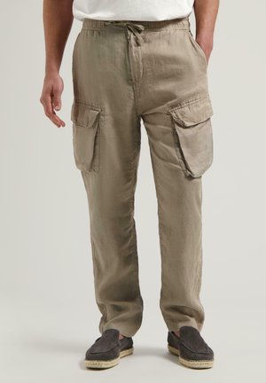 Khaki barvy lněné cargo kalhoty s elastickým pasem, šňůrkou a dvěma velkými bočními kapsami. Nošeny s šedými espadrilkami.
