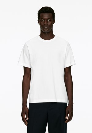 Weißes T-Shirt mit kurzen Ärmeln aus Baumwolle, mit runden Ausschnitt und lockerer Passform. Einfaches Design ohne sichtbare Muster oder Akzente.