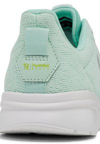 Ljus mintgrön sneaker med meshmaterial, hexagonal häldetalj, vit mellansula och märket "hummel REACH" logotyp. Mjuk textur.