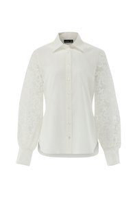 Camicia bianca con colletto classico, maniche trasparenti ricamate a lunghezze intere e chiusura con bottoni. Texture morbida; leggero splendore.