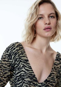 Zwart en beige gestreepte top met een diepe V-hals en textuurstof, met een tijgerstreep patroon.