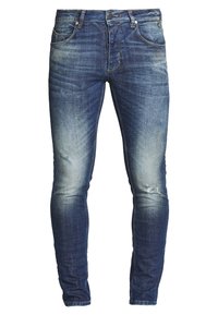 Úzké džínové kalhoty v tmavě modré barvě s mírným vyblednutím, s odřenými místy, pěti kapsami a zapínáním na zip s kovovými doplňky.