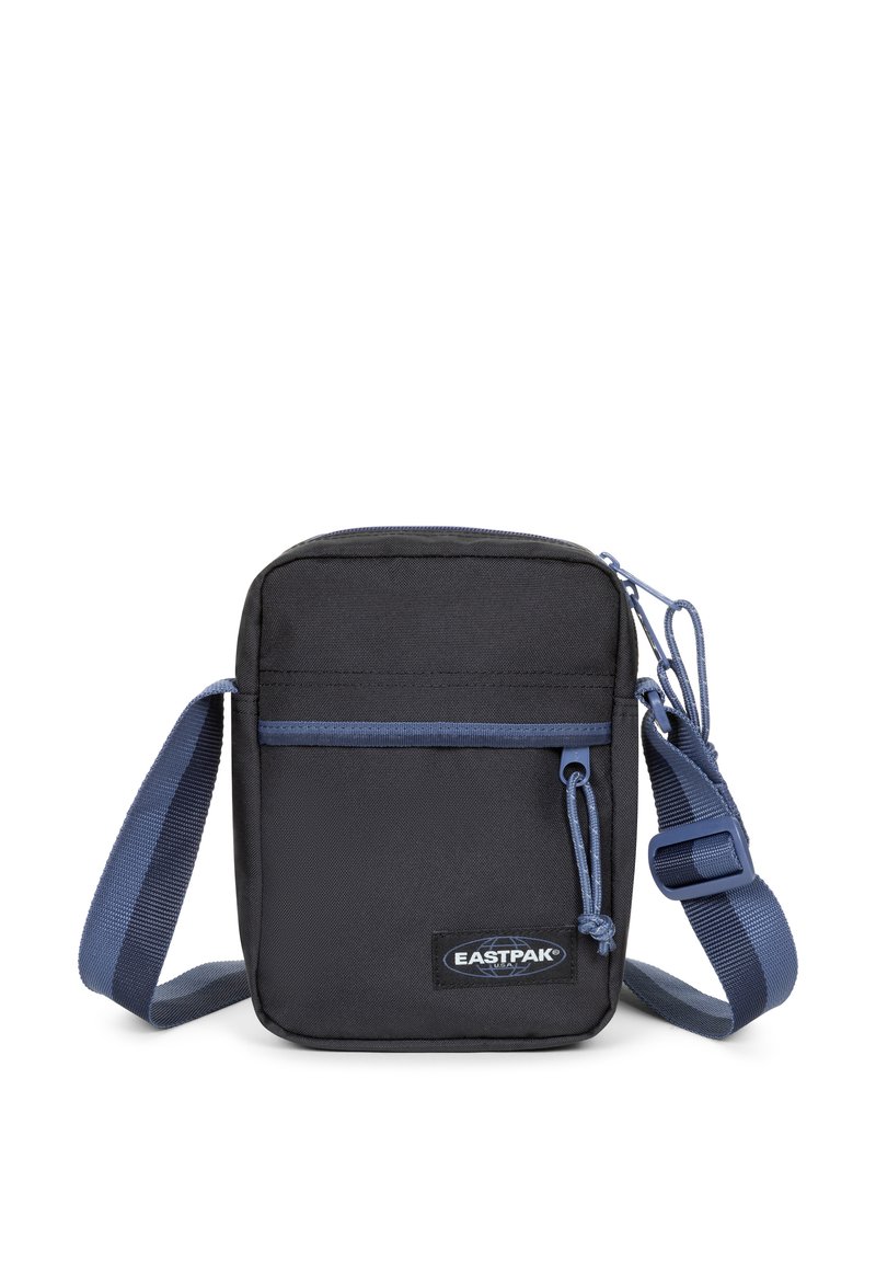 Černá látková krosbody taška s přední kapsou na zip, modrými detaily, nastavitelným popruhem a nášivkou s logem Eastpak. Obdélníkový tvar.