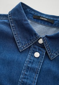 Denim shirt featuring a blue hue, classic collar, silver snap buttons, and contrasting stitching. Soft texture with structured design.