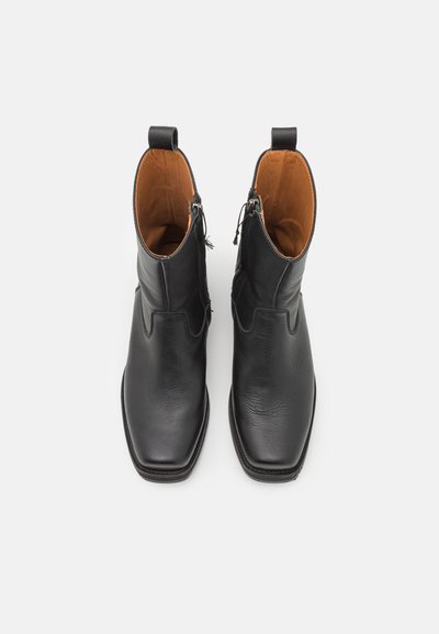 Svarta läderankelboots med fyrkantig tå, sidogylftstängning och tanfärgad inredning. Designade med sömlösa konturer och minimal hårdvara.