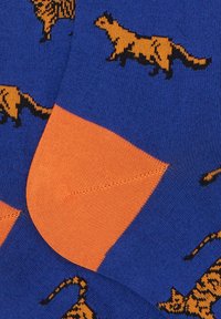 Calzini blu con stampe di gatti neri e arancioni, con tallone e punta arancioni. La texture è liscia ed elastica.
