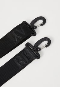 Schwarze Nylongurte mit metallischen Clips an jedem Ende, die eine strukturierte Oberfläche und einen subtilen Logo-Druck auf dem Material aufweisen.