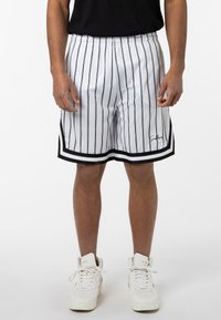 White basketball shorts with black vertical stripes, an elastic waistband, black hem accents, and a logo on the lower left side.