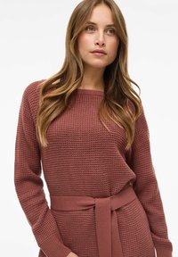 Strukturert genser med lange ermer i en støvete rosalilla farge. Har belte i midjen og en bred rund hals.