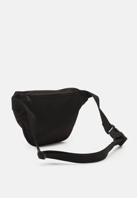 Czarna saszetka na biodra wykonana z trwałego materiału, z zamkiem błyskawicznym i regulowanym paskiem. Wyprofilowany kształt z bocznymi akcentami.