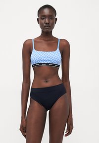 Blue patterned bralette with thin straps, black elastic band featuring the brand name, paired with solid black high-waisted underwear.