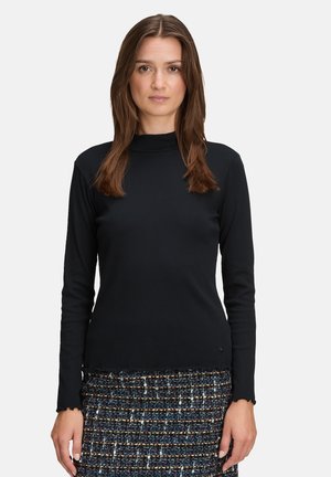 Zwarte top met lange mouwen, hoge halslijn en geschulpte zoom, gecombineerd met een multicolor textuurne broekrok. Glad stof, slanke pasvorm.