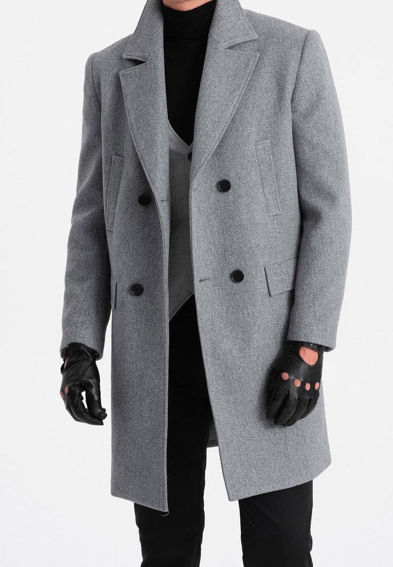 Dvoupřadový šedý vlněný kabát s klopovým límcem, černými knoflíky a bočními kapsami, doplněný šedou vestou a černými rukavicemi.