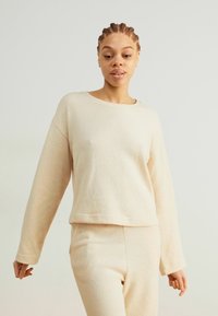 Beige langemouwen top van zachte stof met een ronde hals, een relaxte pasvorm en een iets cropped ontwerp, gecombineerd met bijpassende broek.