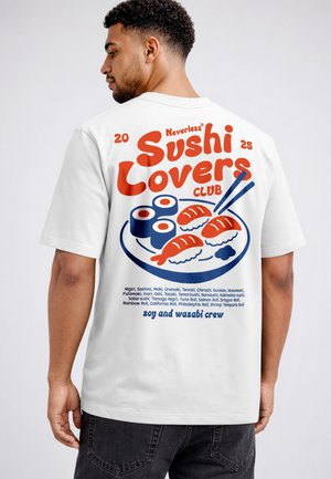 Mann trägt weißes T-Shirt mit rotem und blauem Schriftzug „Sushi Lovers Club“ und Sushi-Illustration auf dem Rücken.