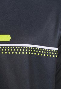 Mörk tyg med en slät textur har ett horisontellt vitt rand och ett mönster av små, hexagonala gula prickar längs botten.