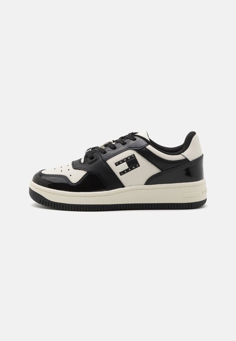 Baskets basses en noir et blanc avec des lacets noirs et un logo "Tommy Jeans" sur le côté, affichées sur fond blanc.