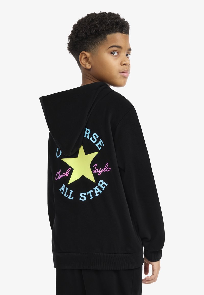 Μαύρο φούτερ με κουκούλα που διαθέτει ένα κίτρινο αστέρι στο πίσω μέρος, με το "Chuck Taylor" σε ροζ και το "All Star" σε μπλε. Μαλακό ύφασμα, άνετη εφαρμογή.