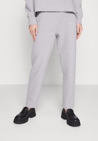 Gray ribbed sweatpants with a relaxed fit, featuring an elastic waistband and side pockets, paired with black chunky loafers.