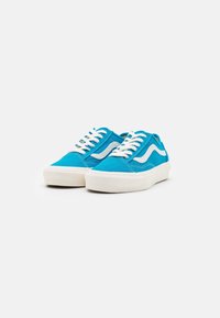 Baskets en toile bleue avec des accents blancs, présentant un design bas, un bout arrondi, des lacets blancs et des semelles en caoutchouc. Tige texturée.