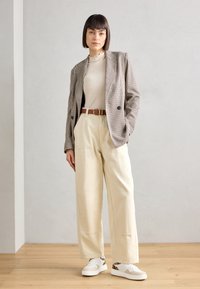 Geverfd blazer, beige geribde top, crèmekleurige wijde broek en witte sneakers met luipaardaccenten. Eenvoudig ontwerp met een relaxte pasvorm.