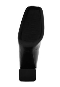 Czarna podeszwa buta na wysokim obcasie o gładkim wykończeniu, z teksturowaną powierzchnią chwytającą i kwadratową podstawą obcasa. Logo widoczne w pobliżu części palcowej.