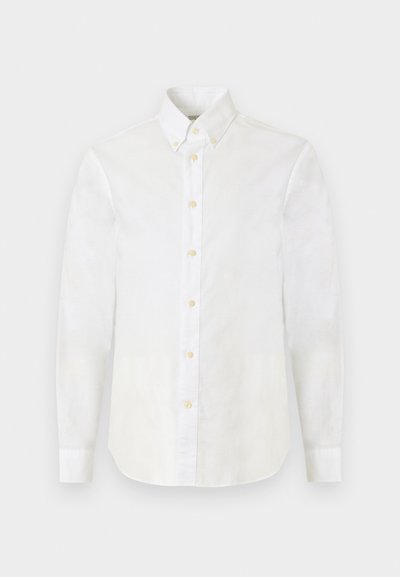 Λευκό πουκάμισο με μακριά μανίκια και κουμπιά, με μυτερό γιακά και μπεζ κουμπιά, παρουσιασμένο σε απλό ανοιχτό γκρι φόντο.