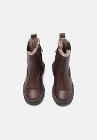 Botas de tobillo de cuero marrón con un interior acolchado, cremallera lateral y una suela de goma negra robusta, con un acabado suave y punta redondeada.