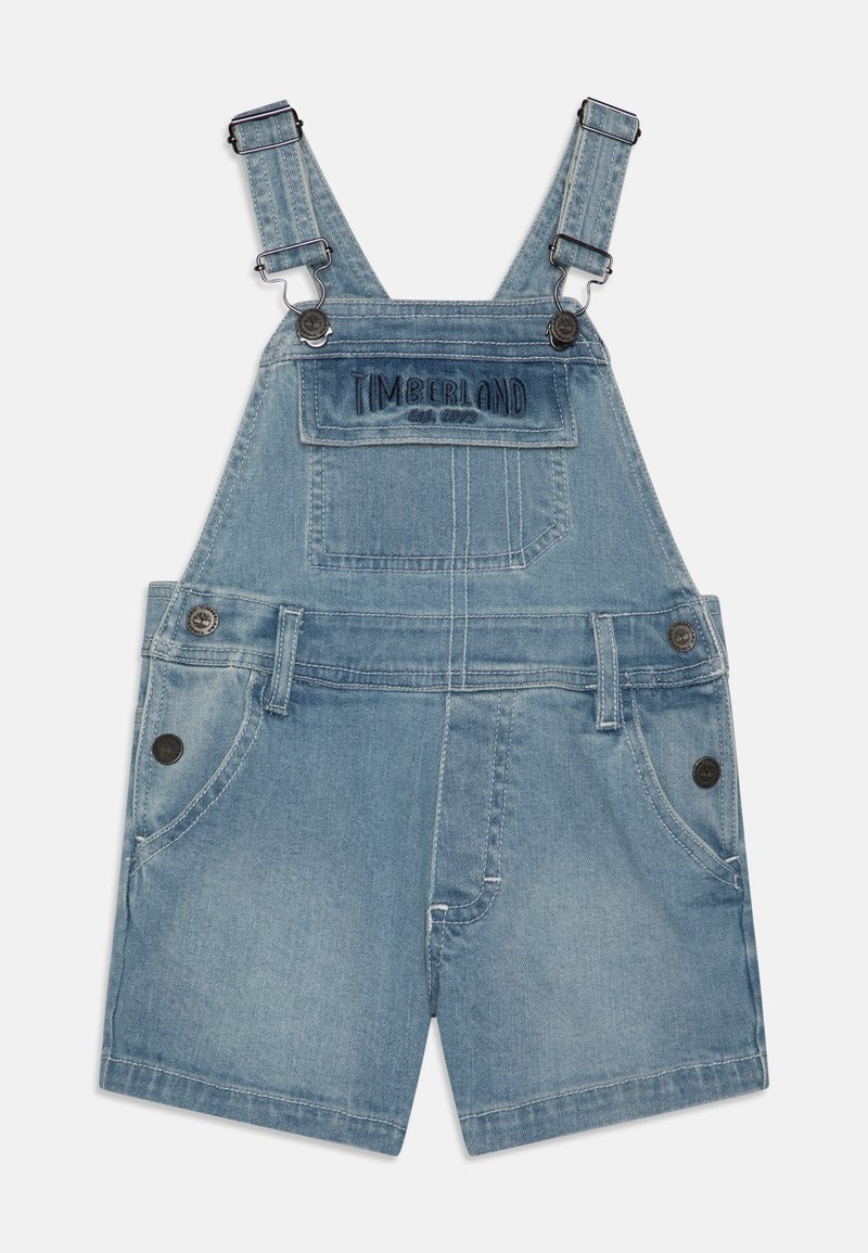 Gaiši zili džinsu kombinezoni ar regulējamām siksnām, priekšējo kabatu ar "Timberland" logo un divām sānu kabatām.