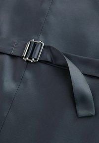 Țesătură gri închis cu o textură netedă, având o cataramă metalică și o panglică de satin trăgându-se pentru prindere.
