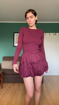 Haut à manches longues côtelé bordeaux avec col rond, associé à une mini-jupe plissée bordeaux, tous deux en tissu léger à texture lisse.