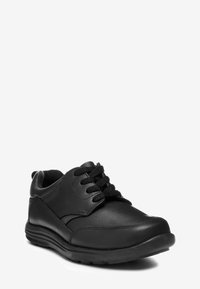 Sneakers en cuir noir avec une pointe arrondie, surface texturée et semelle en caoutchouc robuste. Équipés de lacets et d'un col rembourré pour plus de confort.