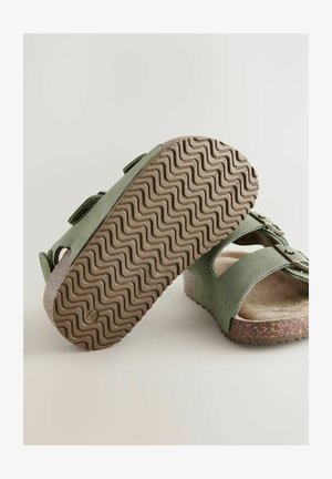Zelené semišové sandály s dvěma nastavitelnými řemínky, korkovou stélkou a vlnitým strukturálním hnědým gumovým podrážkou pro lepší přilnavost a pohodlí.