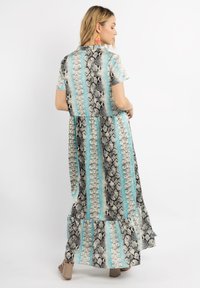 Rochie maxi cu mâneci scurte, având un model cu imprimeu de șarpe în nuanțe de negru, alb și albastru deschis, stratificată cu un tiv volan.