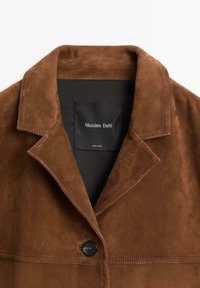 Bruine suède jas met een opvallende kraag, zwarte knoop en subtiele stikdetails. Het binnenlabel zegt "Massimo Dutti."