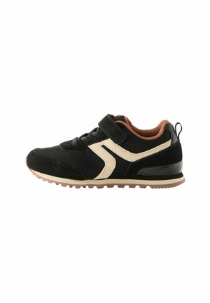 Sneaker noir avec des matériaux en maille et en daim, présentant une bande de couleur crème, un intérieur brun et une sangle Velcro. Semelle en caoutchouc pour une meilleure adhérence.