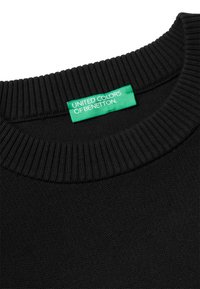 Maglione a collo alto nero a coste con etichetta in tessuto verde con la dicitura "UNITED COLORS OF BENETTON" cucita all'interno del colletto.
