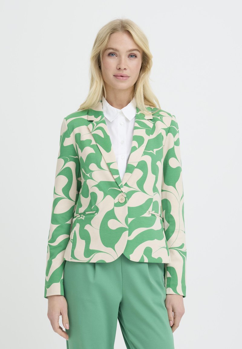Blazer à motif vert et beige avec un seul bouton, deux poches avant et une coupe ajustée, associé à un pantalon vert uni.