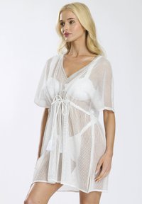 Witte mesh cover-up met korte mouwen, V-hals, trekkoord in de taille en franjes. Lichtgewicht en doorzichtig materiaal.