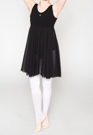Robe de ballet noire avec un corsage ajusté et une jupe transparente, à mi-mollet. Portée avec des collants blancs et des chaussons de ballet rose clair.