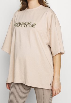 Jasno beżowa, oversize t-shirt wykonana z miękkiego materiału, z teksturowanym graficznym wzorem w panterę w ciemnozielonym kolorze. Boczne rozcięcia dla wygody ruchu.