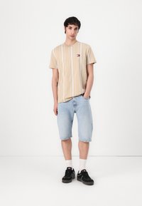 Beige striped t-shirt paired with light blue denim shorts. Accessories include black sneakers and white ankle socks. Simple design, casual look.