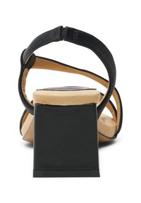 Musta korkokenkä, jossa on leveä lohkokorko, avonainen varvasosa ja sileä nahkapinta. Remmien yksityiskohta pyöristetyllä takana.