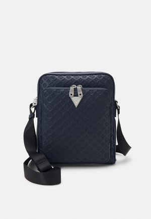 Granatowa torba na ramię z tłoczonym wzorem, przednią kieszenią na zamek, srebrnym trójkątnym logo i regulowanym czarnym paskiem naramiennym z tkaniny.