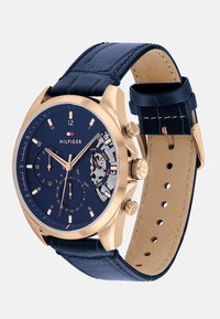 Orologio cronografo dorato con quadrante blu profondo, cinturino in pelle, indicatori di data e giorno, e finitura testurizzata.