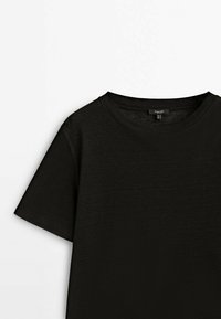 T-shirt noir à manches courtes et col rond, posé à plat sur une surface blanche, montrant la moitié supérieure et l'encolure.