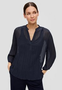 Navy blauwe geplooide blouse met een V-hals, lange mouwen en geplooide manchetten, gemaakt van lichtgewicht, transparante stof. Subtiele textuur en vloeiende uitstraling.