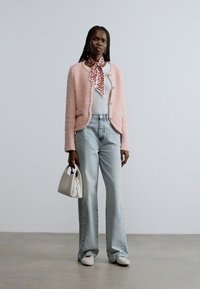 Világosrózsaszín tweed zakó gombokkal, fehér póló, világoskék bővülő farmernadrág, fehér kézitáska, mintás sál és fehér cipő.