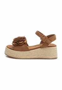 Sandalias de cuña de ante marrón con acento floral, correa ajustable en el tobillo y una suela de plataforma trenzada de yute. Parte superior texturizada y planta suave.